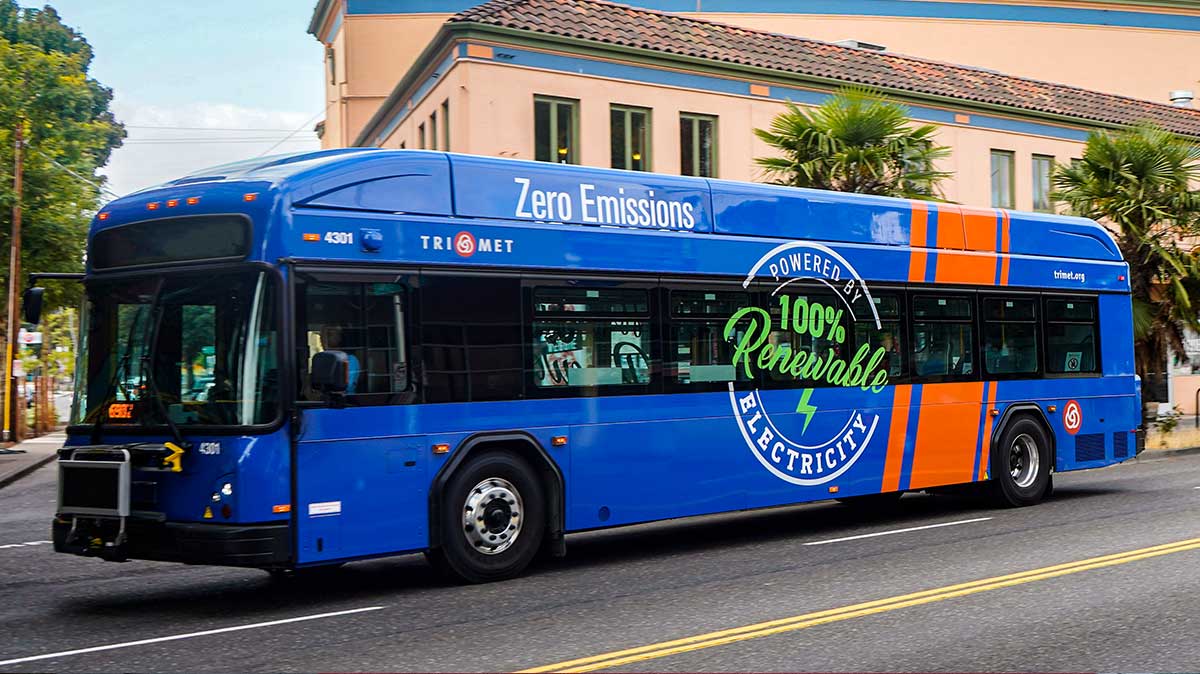 TriMet electric bus with large '100% Renewable' bus wrap on the side.