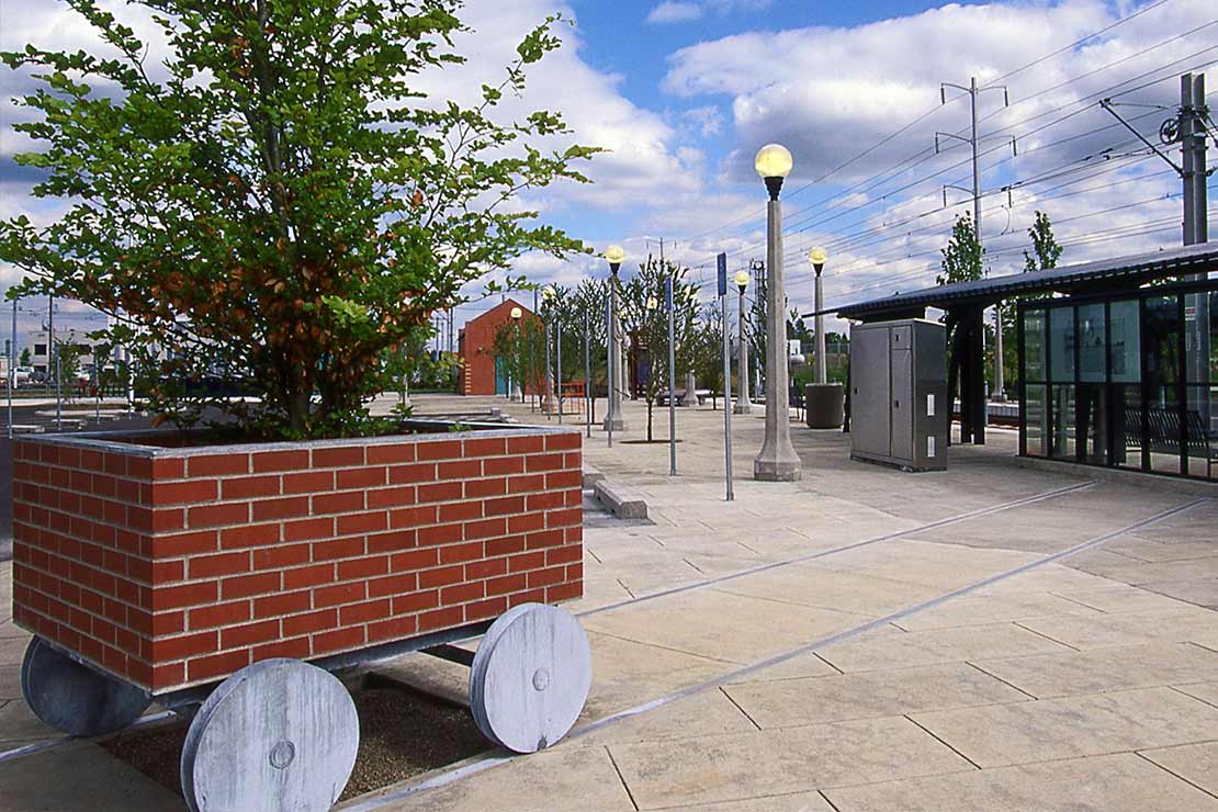 Large brick planter on wooden wheels that looks like a wagon