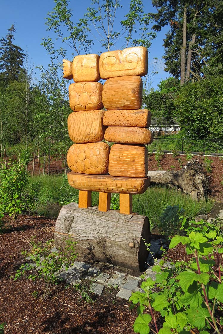 'Allogamy' - carved wooden blocks stacked atop a large segment of a log