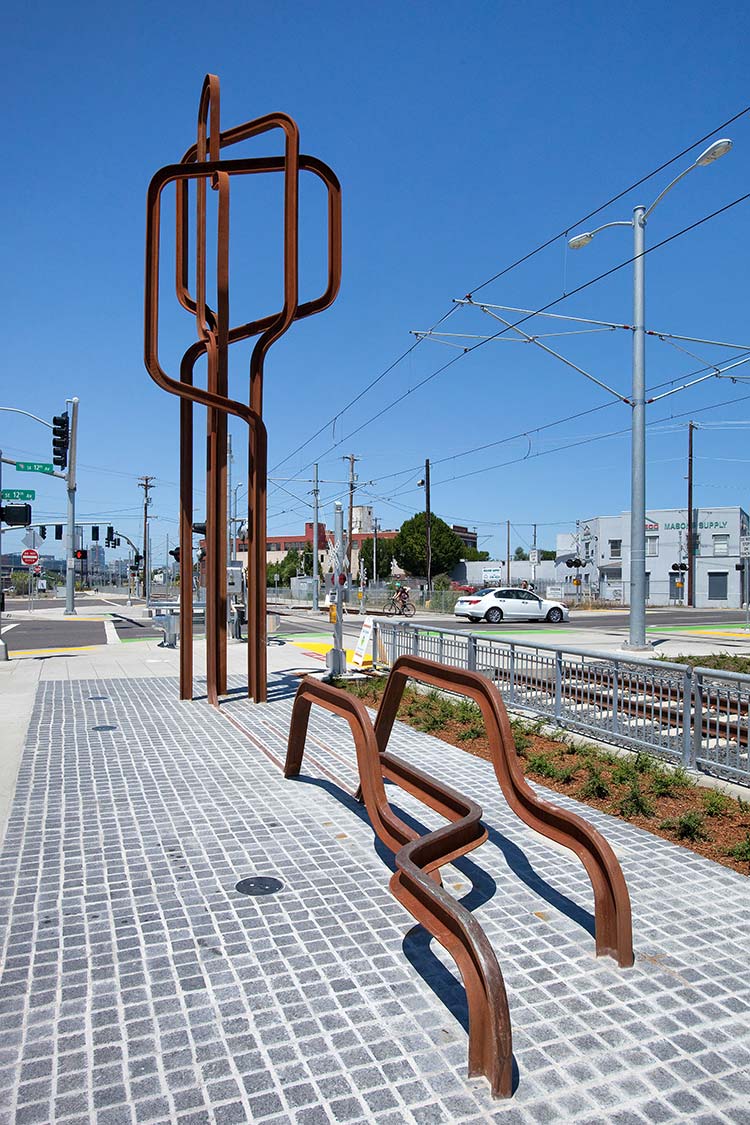 'Intersection' - a metal sculpture made of bent, rusted metal tracks on a tile foundation