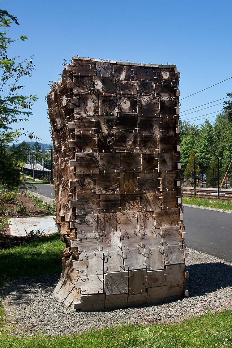 'Sewn' - a tall square sculpture made of wooden blocks connected with steel rings in a sewn pattern